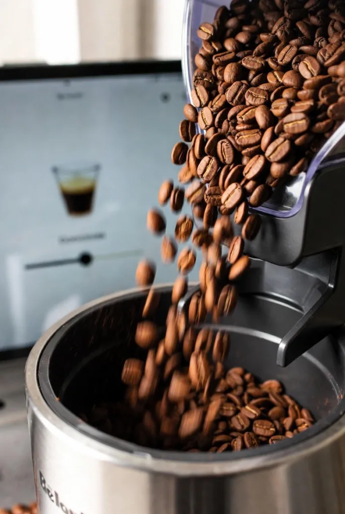 Bean-to-Cup Close-Up Macro shot of fresh beans dropping into a grinder inside the De’Longhi or Breville, with the app open on a tablet in the background showing grind-level slider.